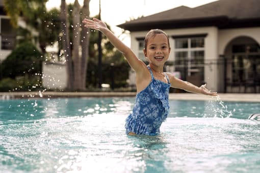 a little girl playing in the water in a pool