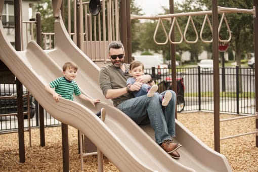 Parent playing with his children on the playground at Lake Nona Water Mark