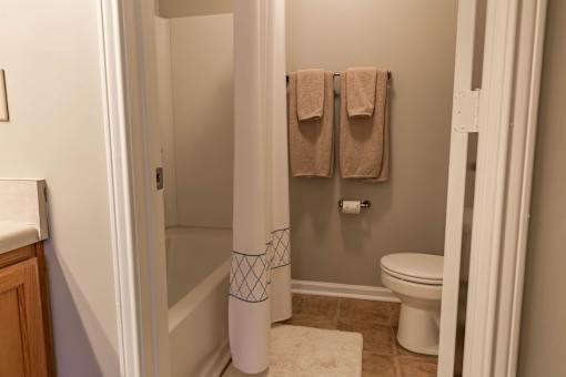 A bathroom with a toilet, a towel rack with two towels, and a white pole with a blue pattern.