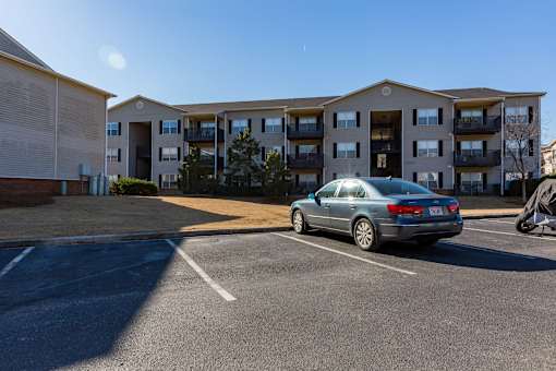 A car is parked in a parking lot in front of a building.
