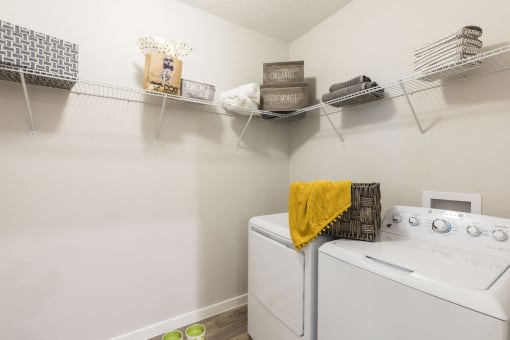 Large laundry room with washers, dryers, and built-in shelving at Residences at The Green in Lakewood Ranch, FL