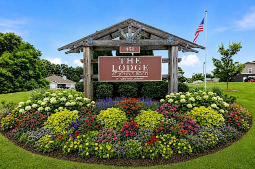 A sign for The Lodge at John's Road is surrounded by flowers.