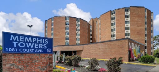 a sign for memphis towers in front of a brick building