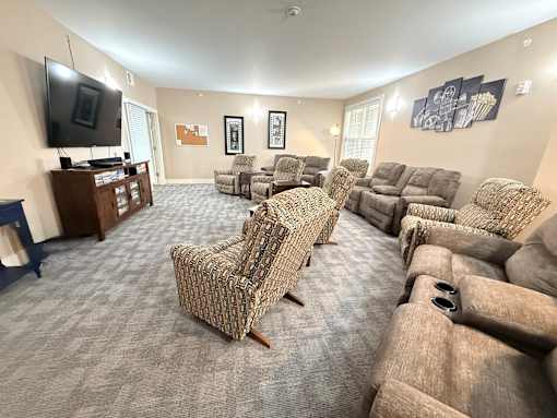 A living room with a grey carpet and a large selection of recliners.at The Lodge at Johns Road Apartments, Huntsville, AL, 35806