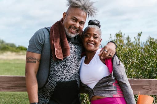a man and woman in work out clothing standing outside and smiling