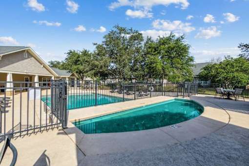 A swimming pool surrounded by a fence and trees.