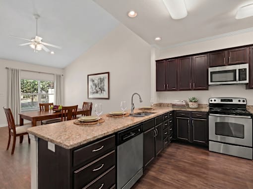 A kitchen with dark brown cabinets and a granite countertop.