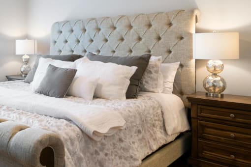 a bed with a tufted headboard and fluffy pillows in a bedroom