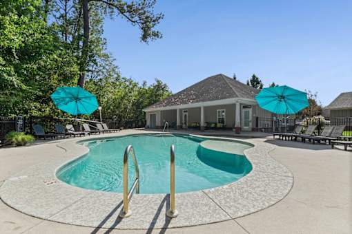 A swimming pool surrounded by trees and a building in the background.
