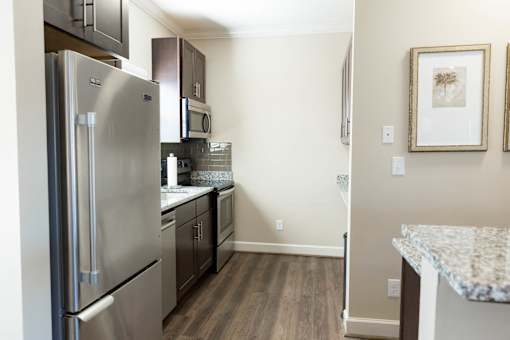 A kitchen with a refrigerator, microwave, and cabinets.