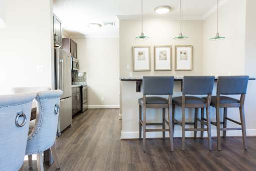 A kitchen with a bar and chairs.