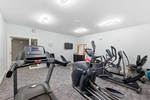 A room with a treadmill, stationary bike, and other exercise equipment.