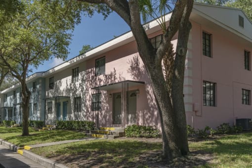 Mature trees and neat sidewalks in front of pastel apartment homes at Terraces at Clearwater Beach, Clearwater