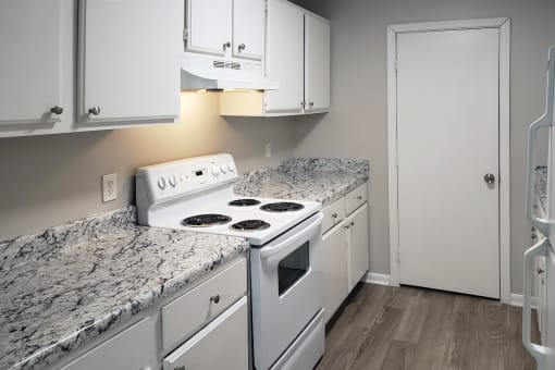 The Bluffs Kitchen with white stove, white cabinets and wood-style flooring at The Bluffs