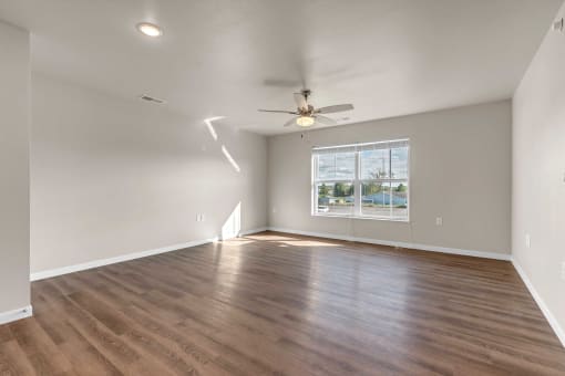 an empty living room with a ceiling fan and a window
