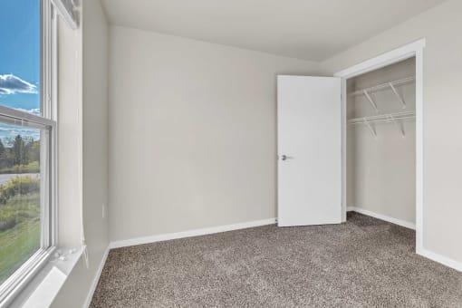 an empty bedroom with a closet and a window