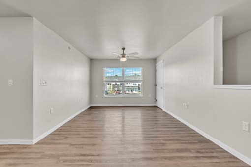 an empty living room with a ceiling fan and a window