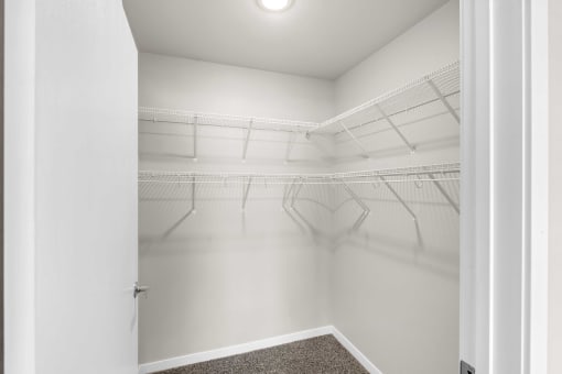 the closet of a studio apartment with white walls and mirrored racks