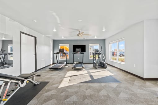a gym with exercise machines and a ceiling fan