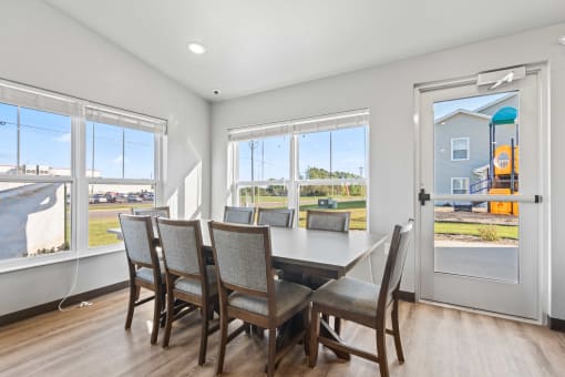 a dining room with a table and chairs and large windows