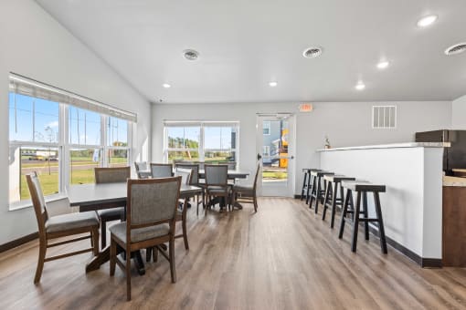 a dining room with tables and chairs and a bar and a kitchen