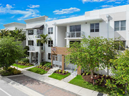 A modern apartment building with a well-maintained garden in front.
