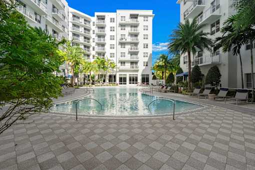 A swimming pool surrounded by a tiled floor and palm trees.
