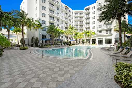 A large white building with a pool in front of it.