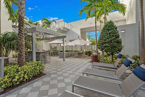 A patio with a checkered floor and several chairs and umbrellas.