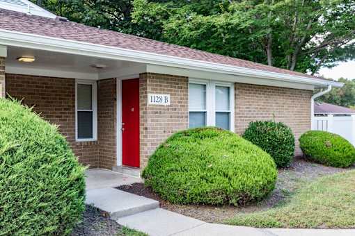 a brick apartment with a red door