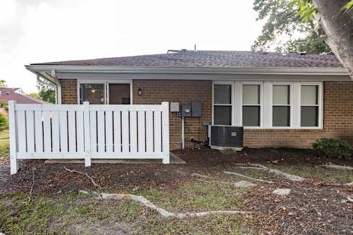an apartment home with a white fence in front of it