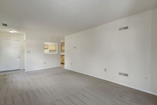 a large empty room with a kitchen in the background