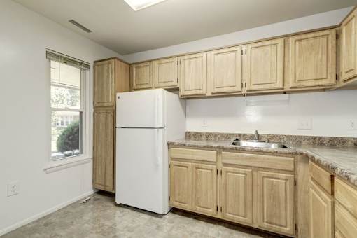 a kitchen with a white refrigerator freezer next to a window
