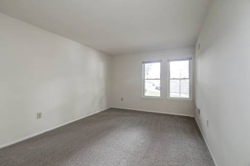 a bedroom with two windows and a carpeted floor