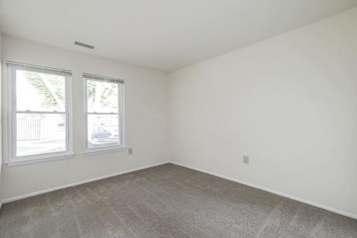 a bedroom with two windows and a carpeted floor