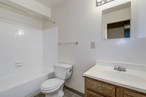 a bathroom with white countertops and wood cabinetry