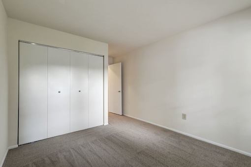 a bedroom with white walls and a closet with a white door