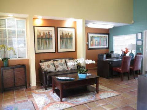 Clubhouse Seating Area with Couch , Area Rug, Coffee Table and Decorations Next to Leasing Desk with Chairs