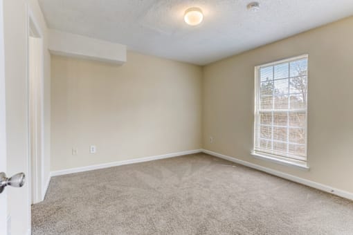 an empty living room with a large window and carpet