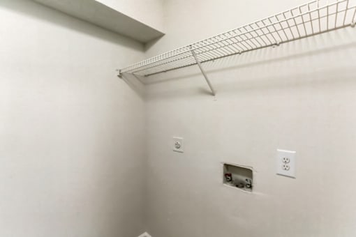 an empty room with a wire shelf on the wall