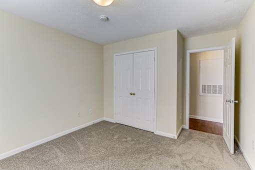 an empty room with a white door and a closet