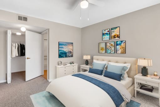 Virtually staged bedroom with wall art, floor rug, night stands, desk lamps, bed, dresser, reach-in closet, and en-suite bathroom