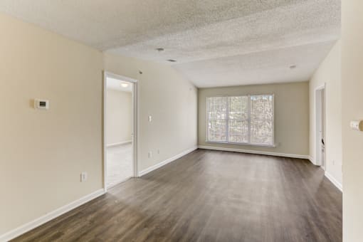 the living room of an empty apartment with wood flooring and a window