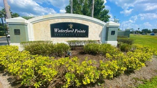 Property Sign with landscaping shrubbery underneath it and trees in the back ground
