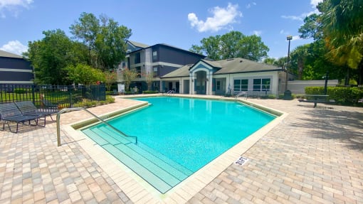 Swimming pool with lounge seating and clubhouse in the background