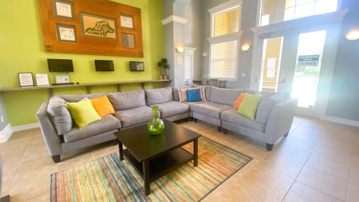 Clubhouse lounge with couch, coffee table, tiled flooring, and floor rug