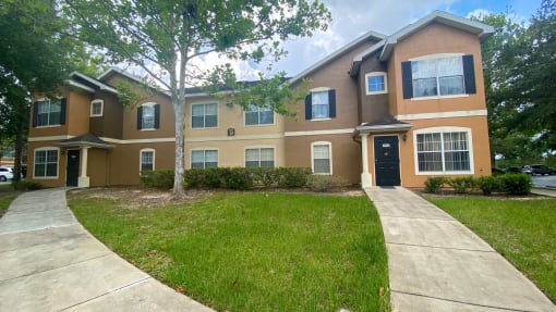 Building exterior with bushes and trees and  a side walk.