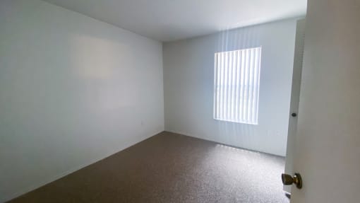 Carpeted Bedroom with white walls and one widow