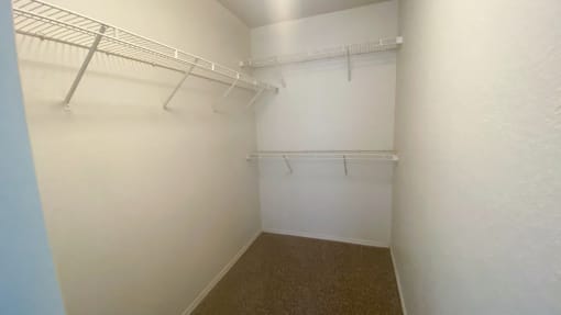 Spacious carpeted closet with mounted metal shelves
