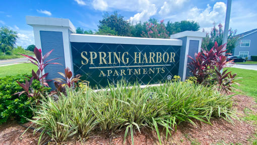Property Sign with landscaping shrubbery underneath it and trees in the back ground